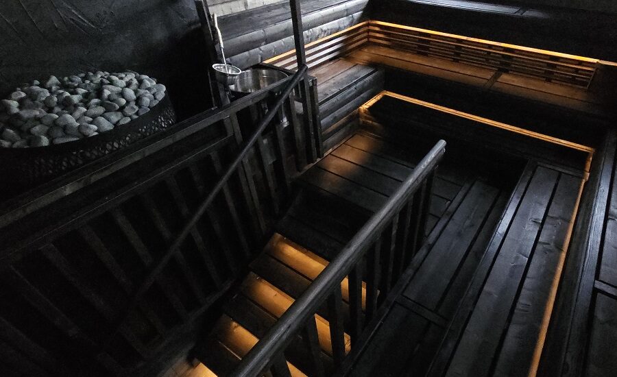 Tummasävyinen bastu, jossa LED-valaistus luo rauhallisen ja tunnelmallisen ilmapiirin. Lauteet kohoavat portaamaisesti, ja nurkassa oleva kiulu sekä kiuaskivet viimeistelevät tyylikkään kokonaisuuden. Löydä uudenlaiset saunavalaistusratkaisut LedStore.fi-verkkokaupasta!